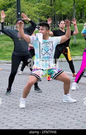 An energetic Zumba dance exercise instructor jumps in the air while leading a class in Flushing Meadows Corona Park in Queens, New York City. Stock Photo