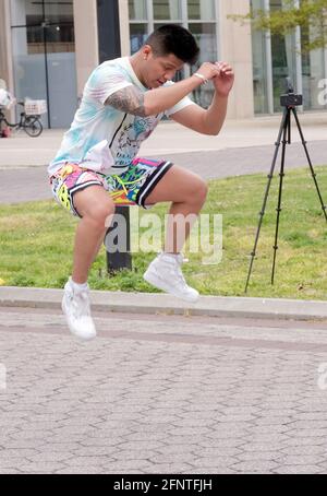 An energetic Zumba dance exercise instructor jumps in the air while leading a class in Flushing Meadows Corona Park in Queens, New York City. Stock Photo