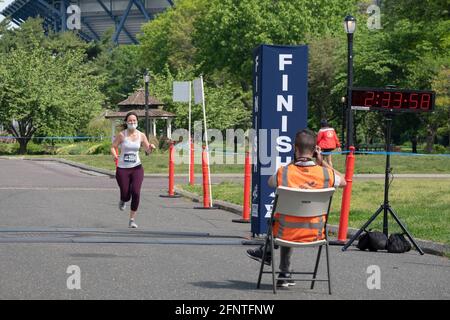 The official race photographer takes a snap of a female finisher approaching the end of the NYCRuns Queens half marathon in Flushing Meadows Corona. Stock Photo
