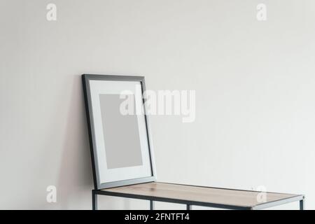 Blank wooden photo frame stands in the interior on a white background. Mockup poster frame. Stock Photo