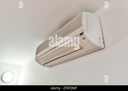 Modern air conditioner hanging on light wall in room Stock Photo - Alamy