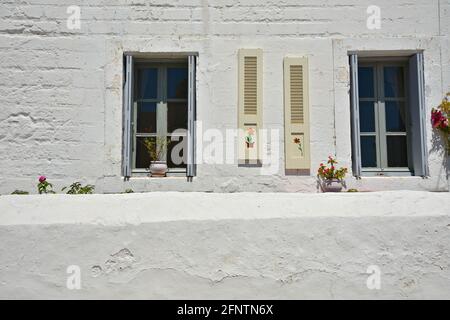 Old rural house with whitewashed walls, grey hand painted window shutters and clay flower pots in Chora, the capital of Kythira island Attica Greece. Stock Photo