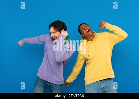 happy young african american man dancing with friend isolated on blue Stock Photo