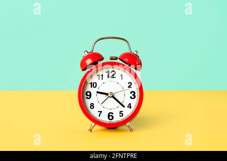 Close up of red vintage alarm clock on a green and yellow background Stock Photo