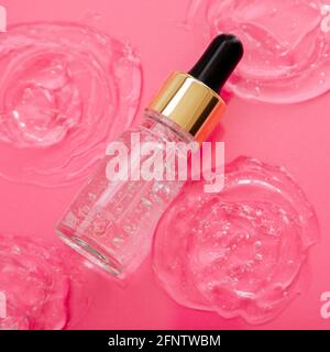 Collagen Serum or hyaluronic serum in dropper on pink color background. Skincare cosmetic product bottle for face skin on Collagen swatch. Cosmetics Stock Photo