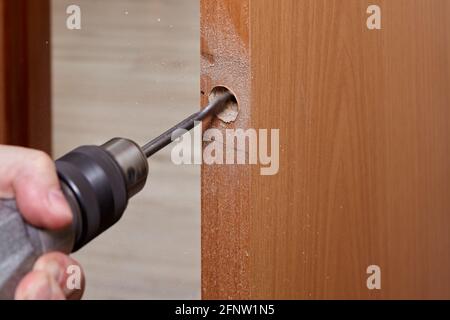 Drilling hole for Latch in wooden interior door with using flat bit. Stock Photo