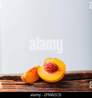 Peaches with leaves on wooden board. Peach in halves with bone