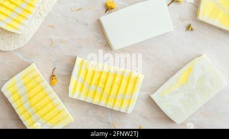 Natural olive soap bars pattern with herbs dry marigold flowers. Many various white homemade bar soaps, spa bath products for body skin care. Hygiene Stock Photo