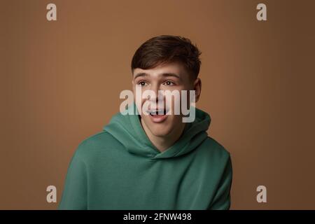 surprised young handsome guy in green sweatshirt Stock Photo