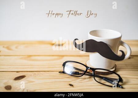 Happy Father's day concept. A black mustache paper, a cup of coffee and glasses on wooden table. Stock Photo