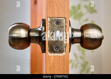 DIY installing of door knob with latch and lock in new chipboard sheet. Stock Photo