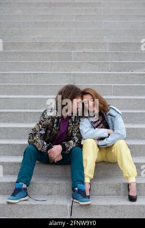 portrait of young couple. sitting outside on steps and embracing each other Stock Photo