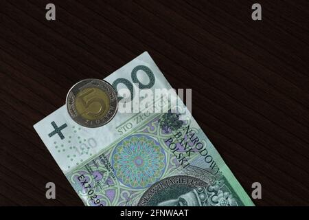 5 Zloty coin falling on 100 Zlotys banknote making it look like 500 Stock Photo
