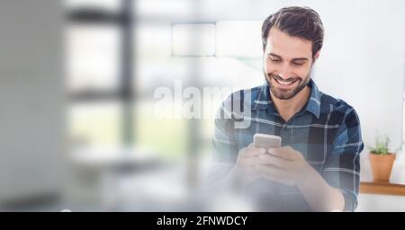 Composition of smiling man using smartphone in office with blurred overlay Stock Photo