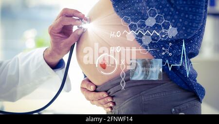 Composition of male doctor touching pregnant woman belly with screen with medical data processing Stock Photo