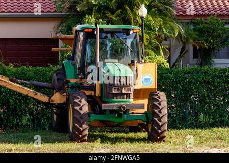 John Deere 6430 Tractor with a long boom for cutting and mowing and hedge clearing canal and ditch embankments of grass, small trees, bushes. Stock Photo
