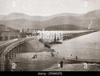 A late 19th Century view of Barmouth Bridge, or Barmouth Viaduct, a single-track wooden railway viaduct across the estuary of the Afon Mawddach near Barmouth, Wales. It is 820 metres (900 yd) long and carries the Cambrian Line. It is the longest timber viaduct in Wales and opened in  1867, one of the oldest in regular use in Britain. Cader Idris mountain can be seen on the far bank. Stock Photo