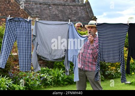 Man hanging washing on clothes line with pegs in the garden Britain, Uk.  domesticated male drying outside exterior household chores jobs work men  Stock Photo - Alamy