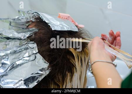 Woman dyes her hair in a barbershop, the process of dyeing her hair with foil. new Stock Photo