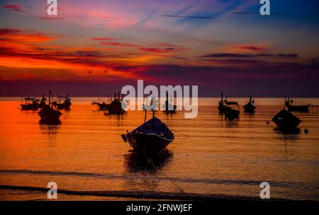 Silhouette fishery boats in the sea with sunset warm low lighting and ...