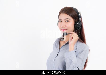 Portrait of happy smiling female customer support phone operator short hair, wearing a white shirt with headset standing one side holding the earphone Stock Photo