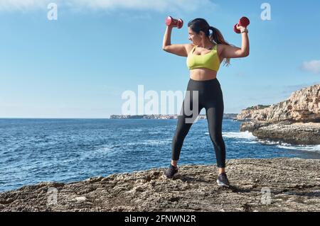 Latin woman, middle-aged, wearing sportswear, training, doing physical exercises, plank, sit-ups, climber's step, burning calories, keeping fit, outdo Stock Photo