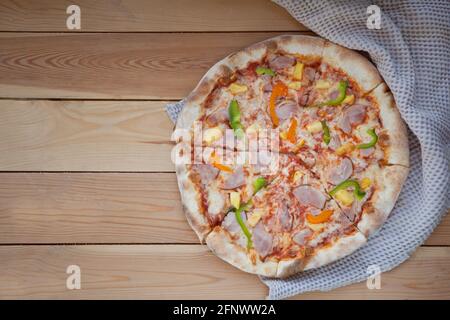 rounded tasty pizza with pepper. Sliced home made pizza on wooden rustic background Stock Photo