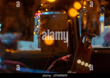 Rear side window view of a red snow-covered vintage car with festive new year lights and decorations Stock Photo