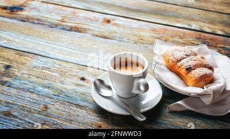 View from above. Cup of hot Italian espresso coffee and croissants on a light blue rustic wooden background. Food and drink. Lifestyle. Stock Photo