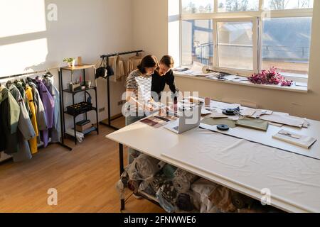 Two dressmaker work in studio with fabric samples for new collection. Team of designers in atelier Stock Photo