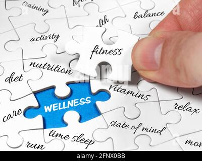 Closeup male hands holding missing jigsaw white piece to complete or solve wellness board puzzle. Fitness is the key concept image Stock Photo