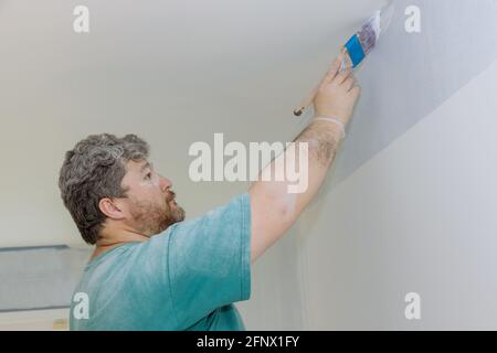 Professional painter using a brush to paint on wall Stock Photo