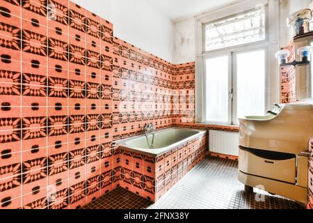Interior of old fashioned bathroom with bathtub and walls decorated with colorful mosaic tiles in retro styled apartment Stock Photo