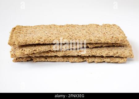 heap of light brown multigrain rye crispbreads isolated on white background, bread cracker snacks, side view Stock Photo