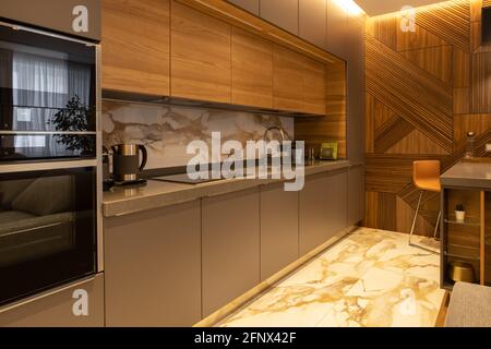 Interior details. Kitchen in a modern apartment. Natural materials. Household appliances, kettle, coffee machine, built-in oven, microwave. Bar counte Stock Photo