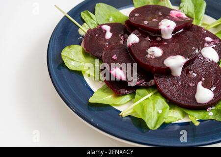 Beet and chicory salad with garlic aioli on a plate on a white marble background. Fresh and healthy vegetables concept. Stock Photo