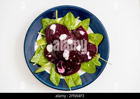 Beet and chicory salad with garlic aioli on a plate on a white marble background. Fresh and healthy vegetables concept. Stock Photo