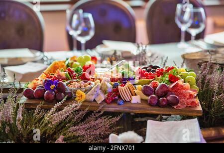 fruits with cheeses, salami, nuts on a wooden board served on a table in a restaurant Stock Photo