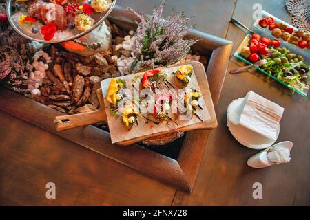 bruschetta with baked pepper and microgreens are served on a wooden board on a table in a restaurant closeup