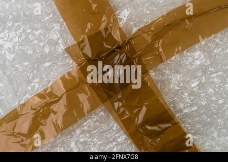 Brown adhesive tape on packaging cellophane film. Close-up. Abstract background. Delivery concept Stock Photo