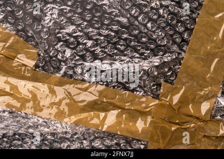 Black bubble wrap with brown wrinkled adhesive tape. Close up. Abstract dark colorful background Stock Photo