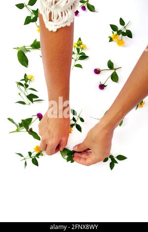 Floral pattern with hand, pink clover and yellow wildflowers on white background. Flat lay, top view. Stock Photo