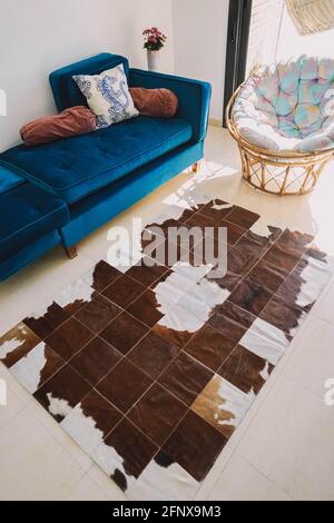 A living room decorated with a green velvet sofa and a cowhide rug Stock Photo