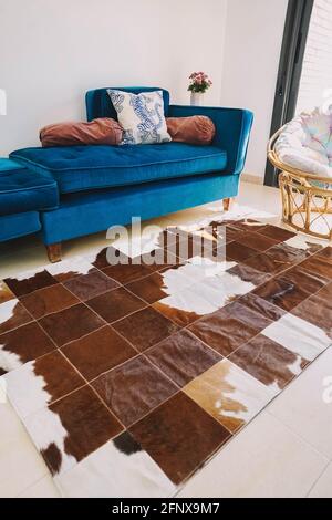 A living room decorated with a green velvet sofa and a cowhide rug Stock Photo
