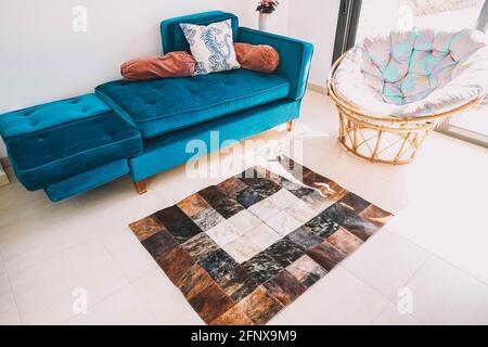 A living room decorated with a green velvet sofa and a cowhide rug Stock Photo