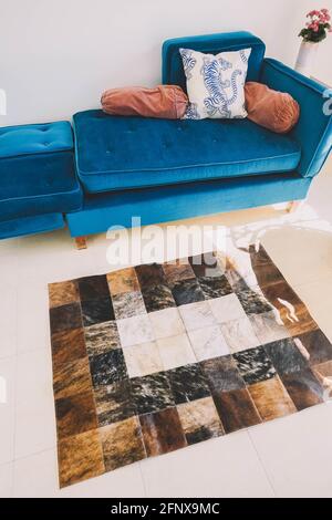A living room decorated with a green velvet sofa and a cowhide rug Stock Photo