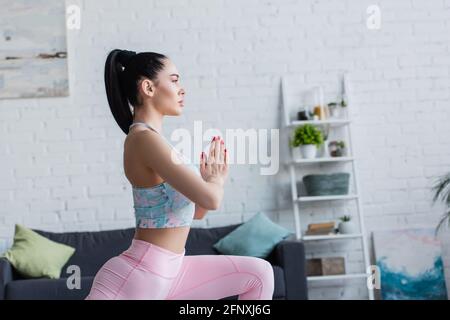 side view of young sportswoman training with praying hands at home Stock Photo