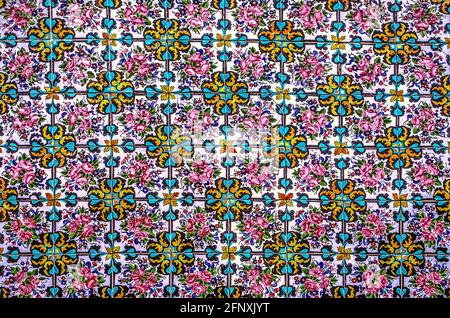 Colorful background with a bright floral pattern assembled from painted ceramic tiles on  the wall of the Golestan Palace Stock Photo
