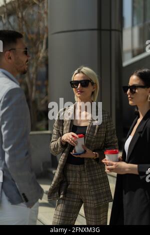 Three well suited business people are talking on their break Stock Photo