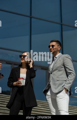 Three well suited business people are talking and smiling Stock Photo